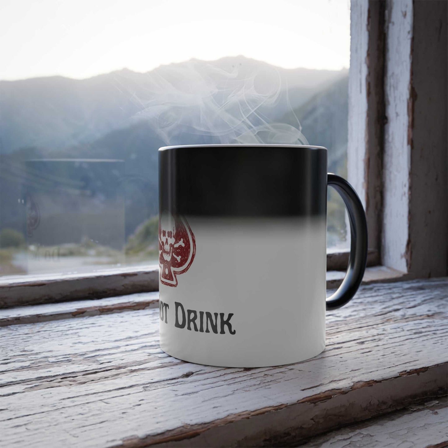 Color Morphing Mug with Poison Skull design on a windowsill with mountains in the background.