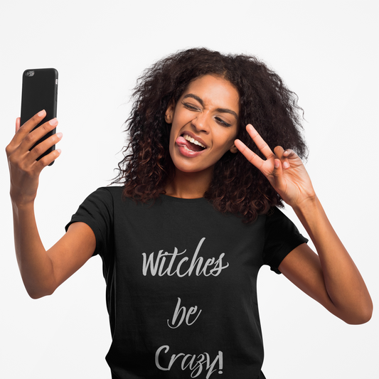 Young woman taking selfie wearing black unisex short sleeve tee with "Witches be crazy!" Halloween graphic.