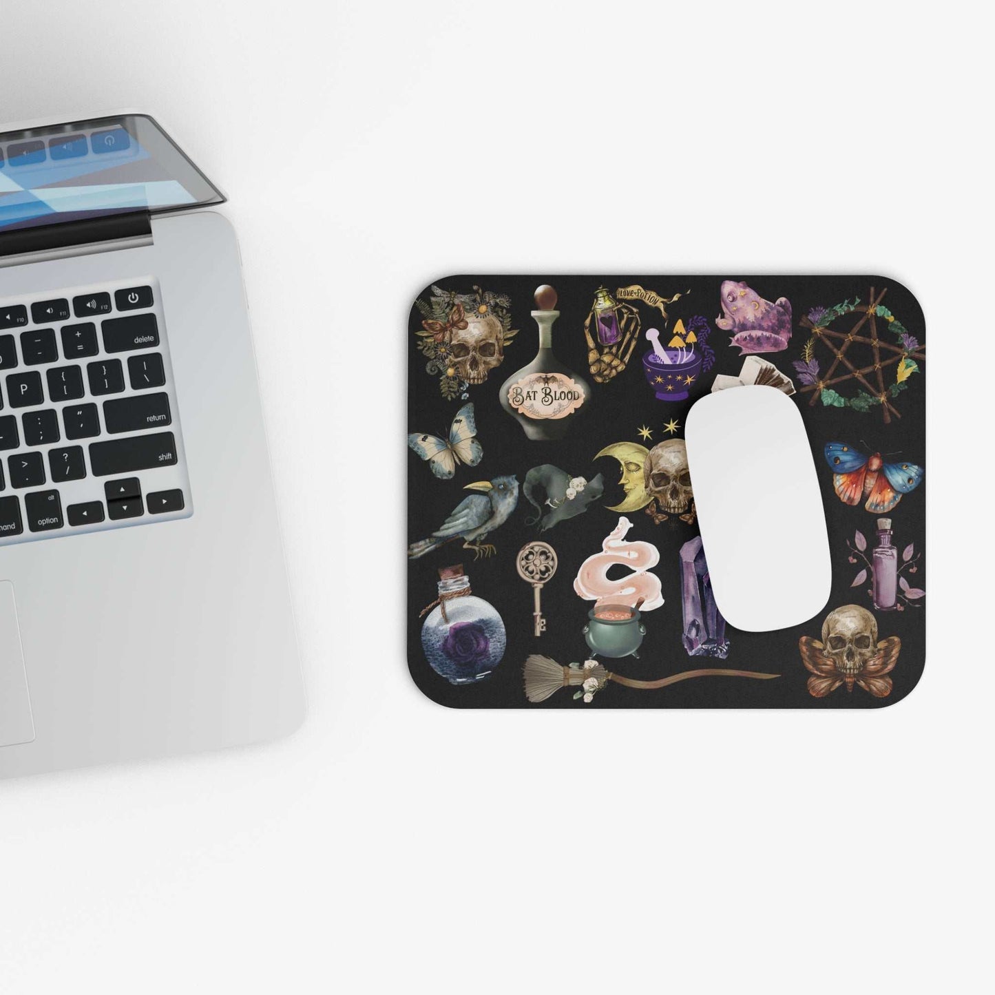 Gothic witchcraft mouse pad with skull and potion design on workspace.