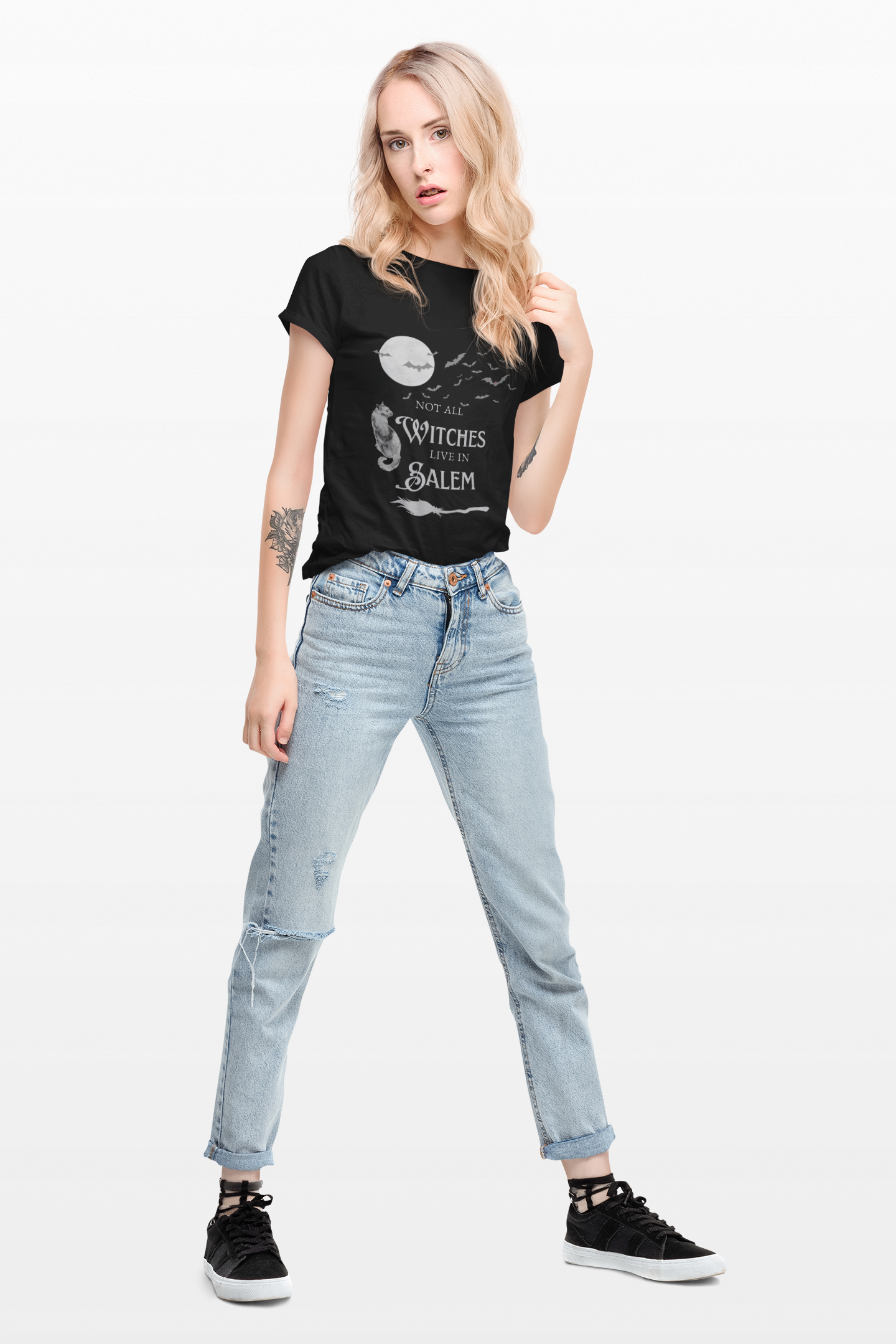 Woman wearing black "Not All Witches Live in Salem" t-shirt with moon and cat design paired with light blue jeans and black sneakers