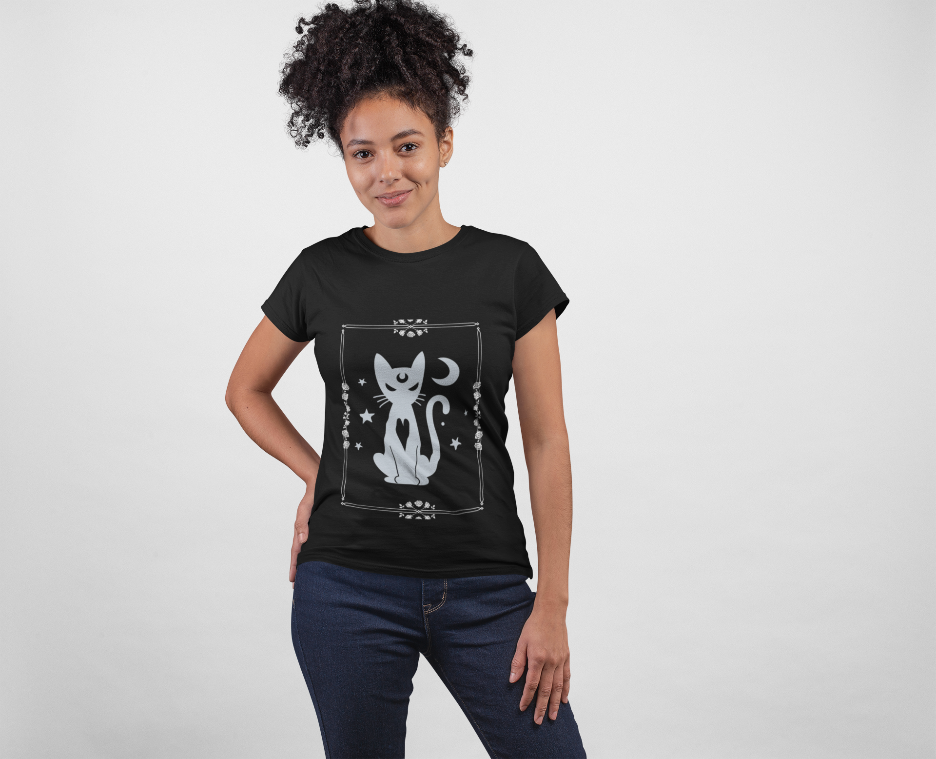 Black unisex t-shirt featuring a mystical white witchy cat design with stars and crescent moon, worn by a woman.