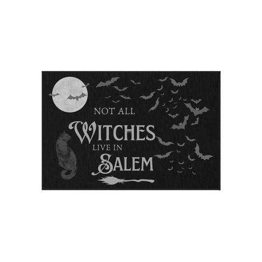 Black Halloween-themed outdoor rug with bats, black cat, broom, moon, and "Not All Witches Live in Salem" text