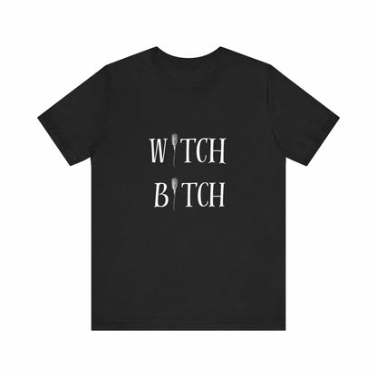 Black unisex jersey short sleeve tee with "WITCH BITCH" white text and broomstick graphic design.